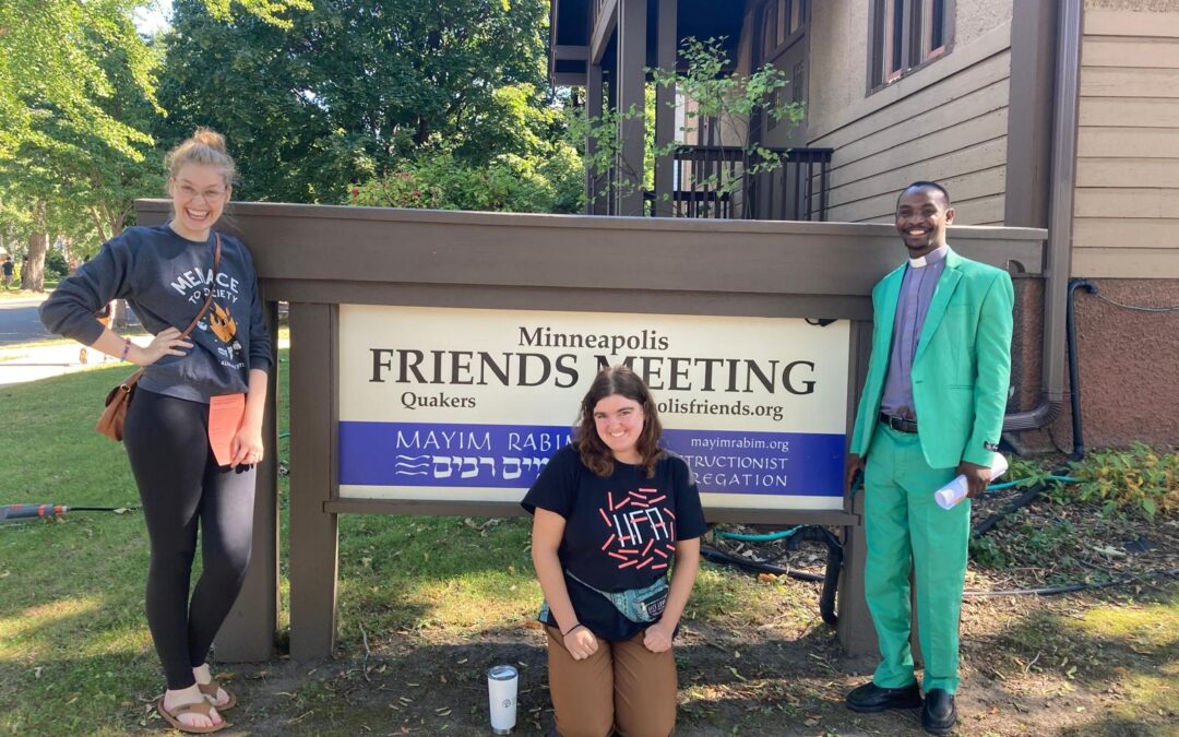 Three people standing in front of the Minneapolis Friends sign.