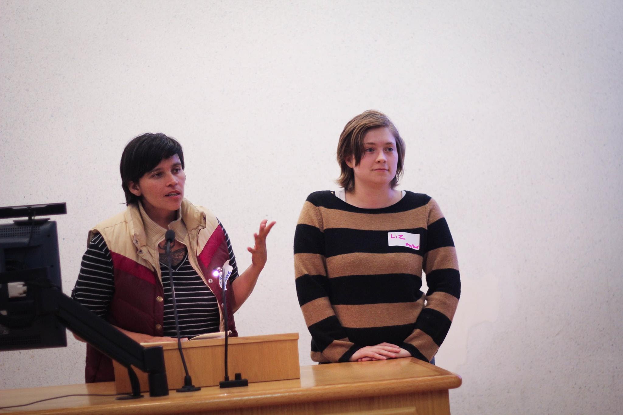 Liz and Ana standing at a podium as presenters